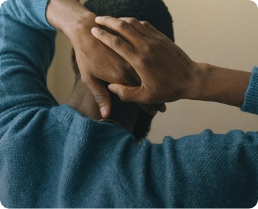 A clinician's hand resting reassuringly on a patient's head.