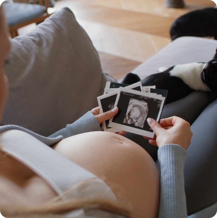 An expecting mother holding an ultrasound photograph of her baby.