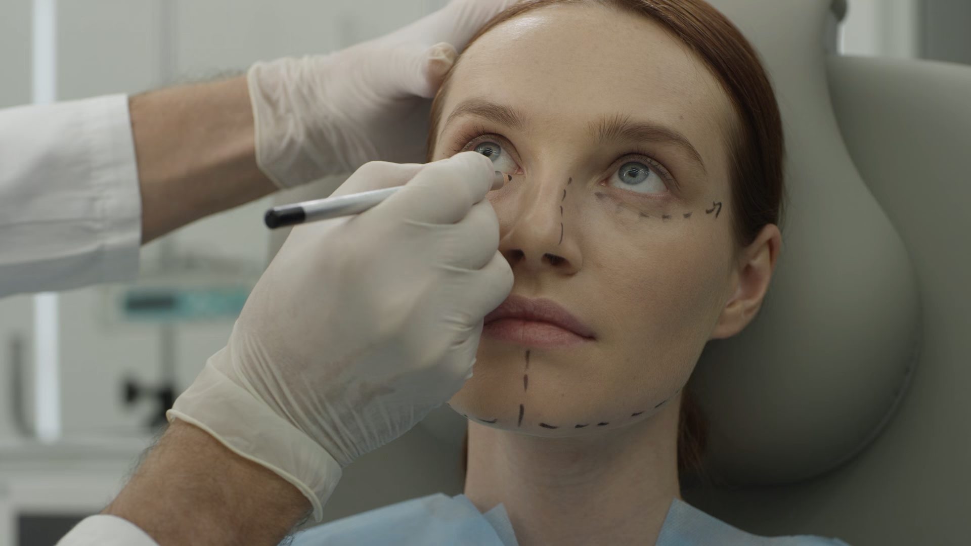 A surgeon marking pre-operative guide lines on a patient's face.